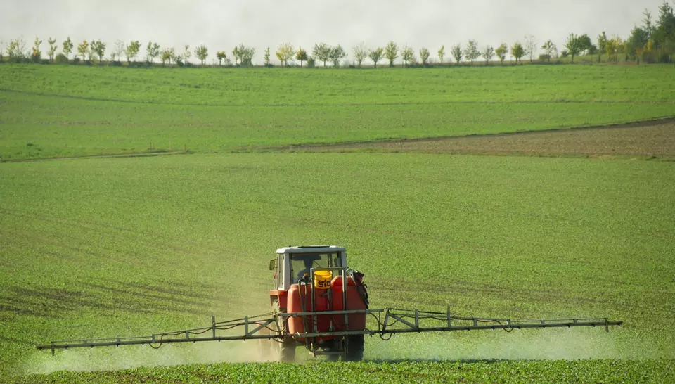 Abbildung eines Traktors der ein Feld düngt 