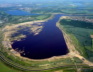 Luftaufnahme eines großen Stausees oder Wasserreservoirs, umgeben von Hügellandschaft.