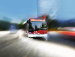 Schnell fahrender Bus auf einer Straße, Bewegungsunschärfe betont die Dynamik.