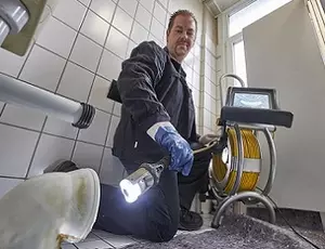 Aufnahme eines Mannes der mit einer Taschenlampe in ein Rohr leuchtet