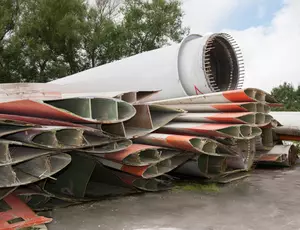 Aufnahme einer auseinandergebauten Windkraftanlage die gestapelt auf einem Haufen liegt 