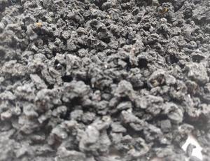 Nahaufnahme von getrocknetem Klärschlamm. Der Klärschlamm ist körnig und hat eine gräuliche Farbe.