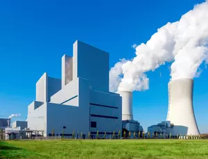 Das Kohlekraftwerk der LEAG in Boxberg. Eine riesen große weiße Anlage, mit zwei weißen Kühltürmen aus denen Dampfwolken rauchen. Im Hintergrund, der stahlend blaue Himmel.