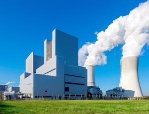  Das Kohlekraftwerk der LEAG in Boxberg. Eine riesen große weiße Anlage, mit zwei weißen Kühltürmen aus denen Dampfwolken rauchen. Im Hintergrund, der stahlend blaue Himmel.
