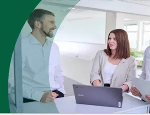 Drei Menschen schauen lachend auf einen Laptop