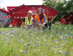 Zwei Frauen auf einer Bienenwiese vor einem Veolia Container