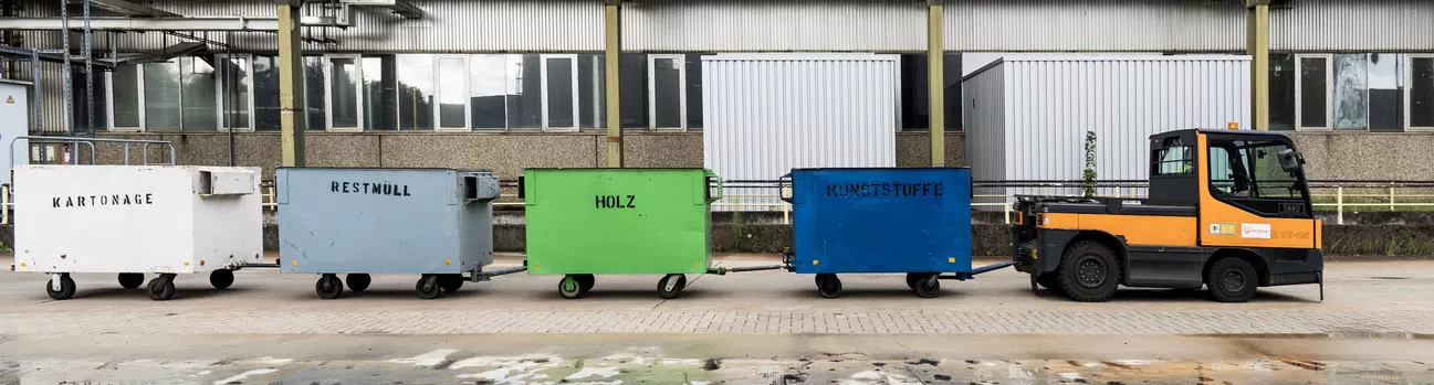 Ein kleiner LKW zieht Container über den Hof