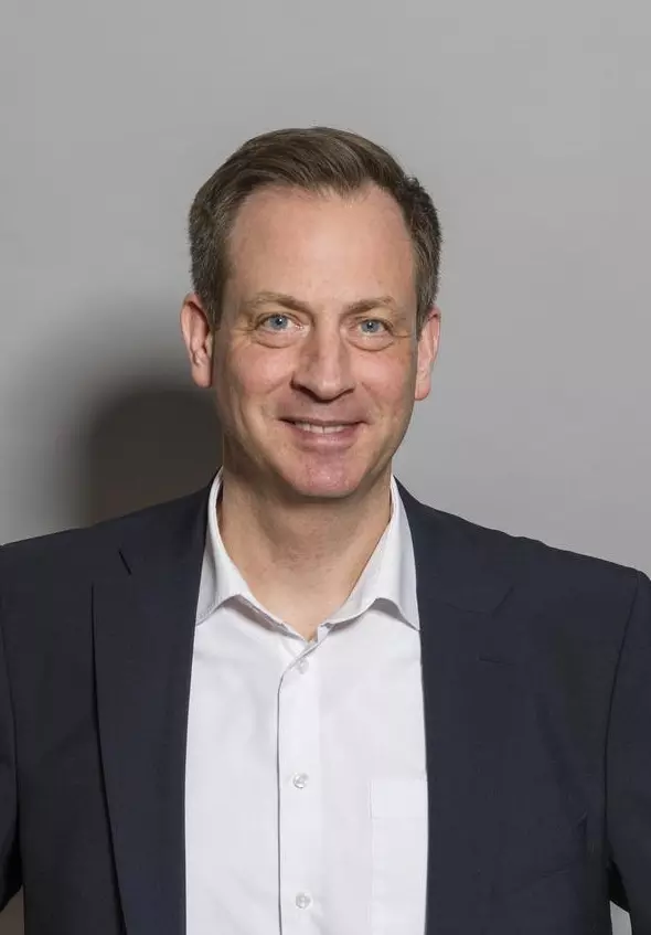 Porträtaufnahme: Ein Mann mittleren Alters. Er trägt einen dunkelgrauen Anzug und ein weißes Hemd.