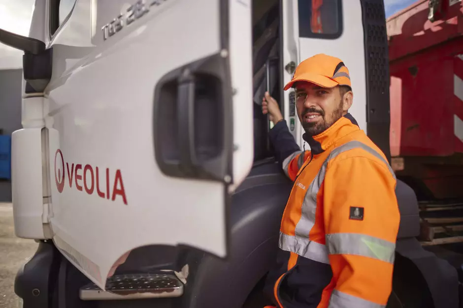 Ein Mitarbeiter von Veolia steht an der geöffneten Tür seines LKWs